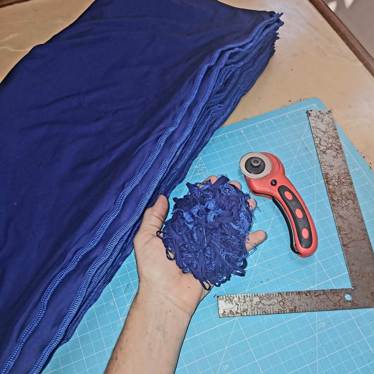 A hand holding a bundle of freshly cut navy neck socks above the cutting mat