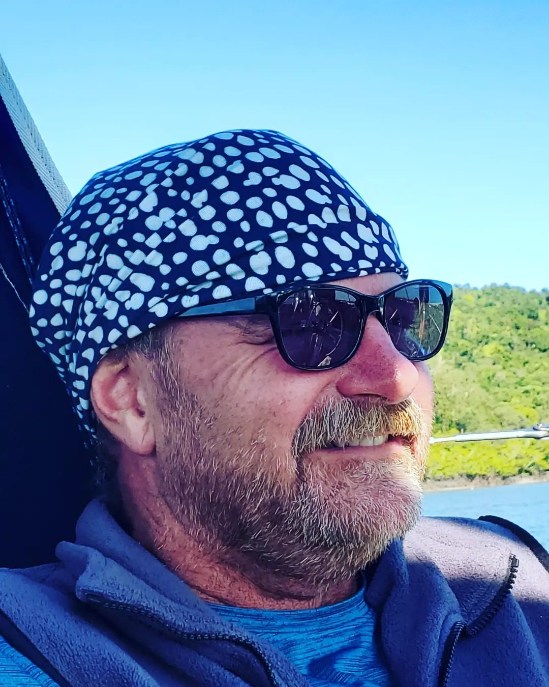 Dave on deck in the sun with a navy and white spotted neck sock worn up on his head